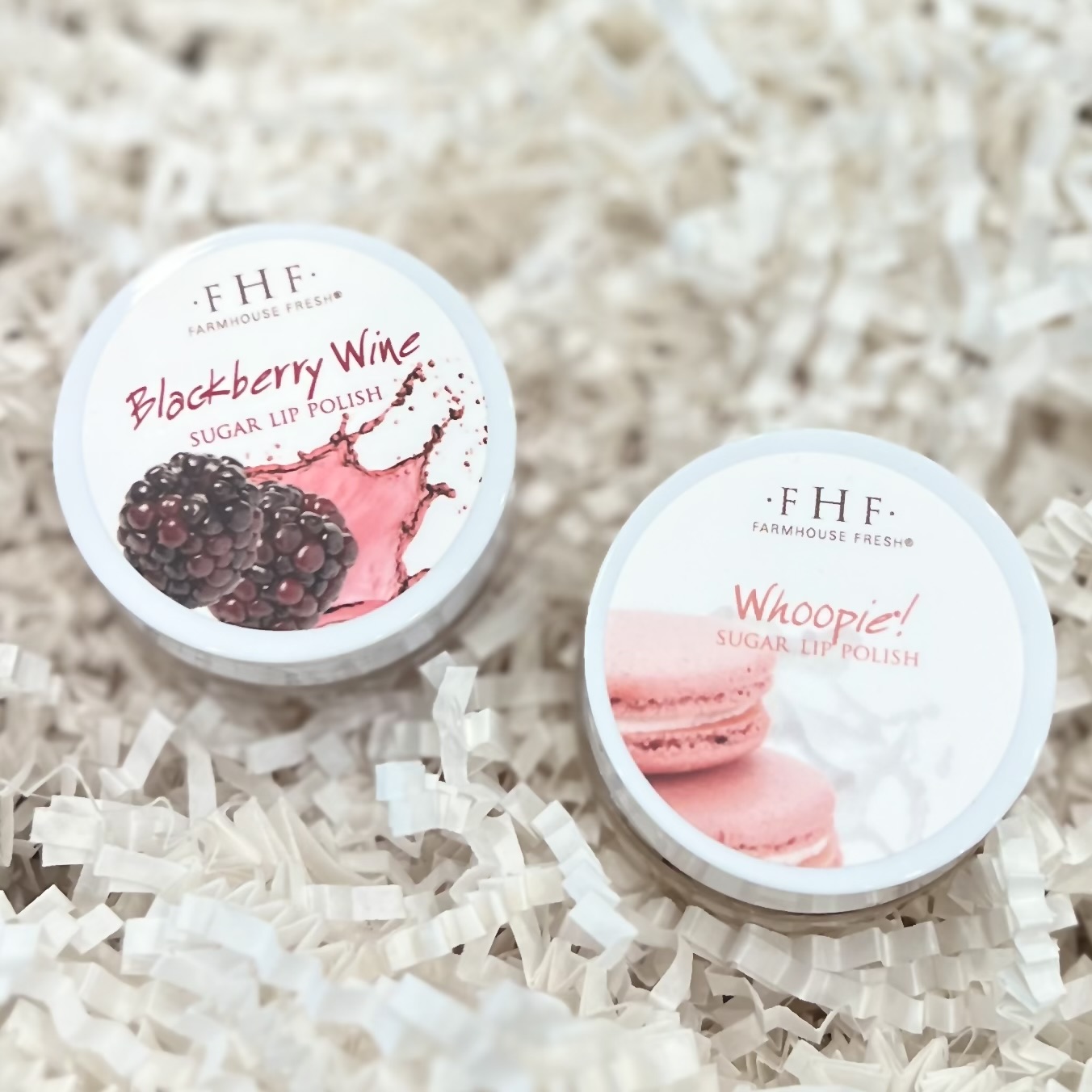 FarmHouse Fresh's Blackberry Wine and Whoopie lip polishes sit in a basket of white crinkle paper.