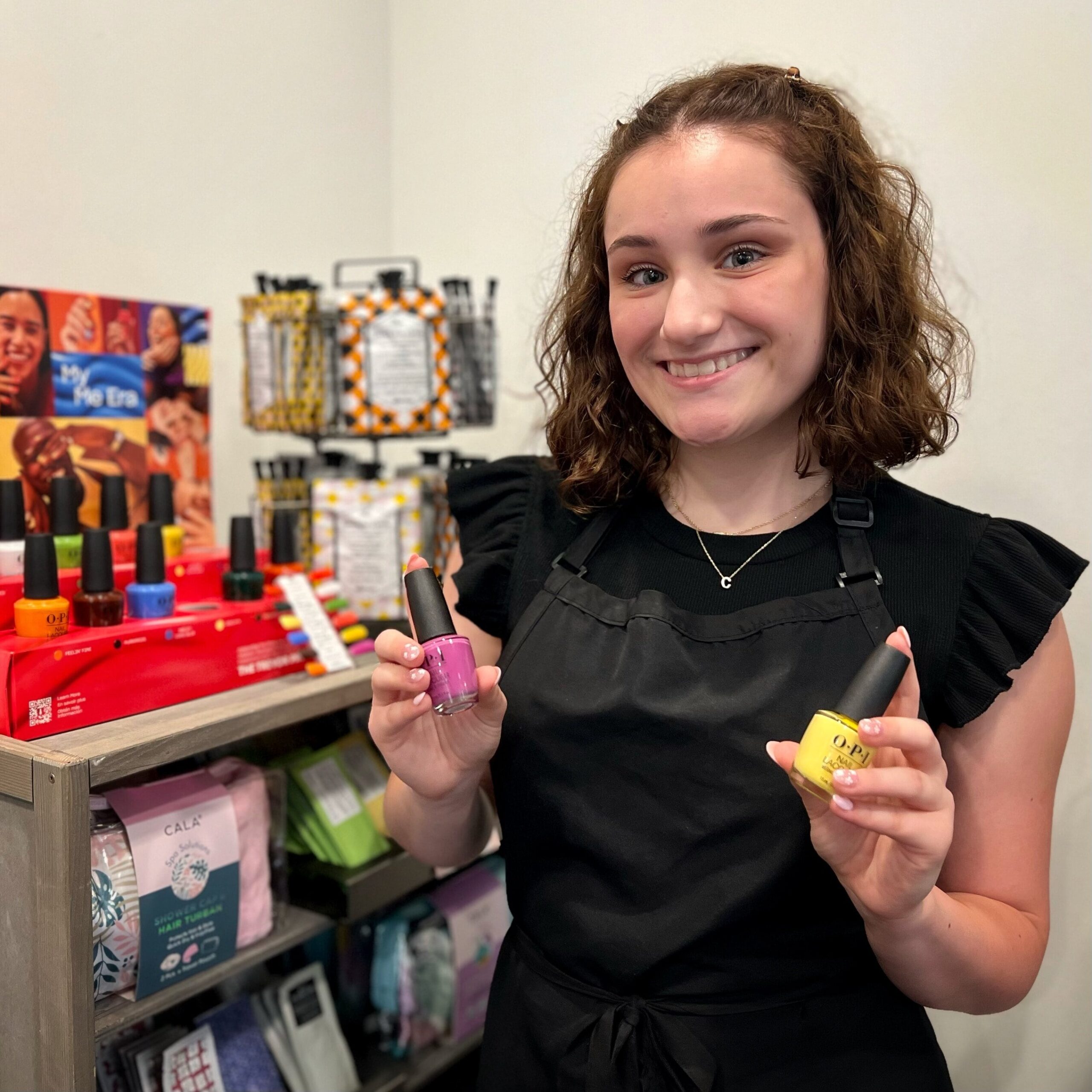 Our junior hair stylist Erin holds OPI's My Me Collection nail polishes in the shades "Bee-FFR" and "I Can Buy Myself Violets."