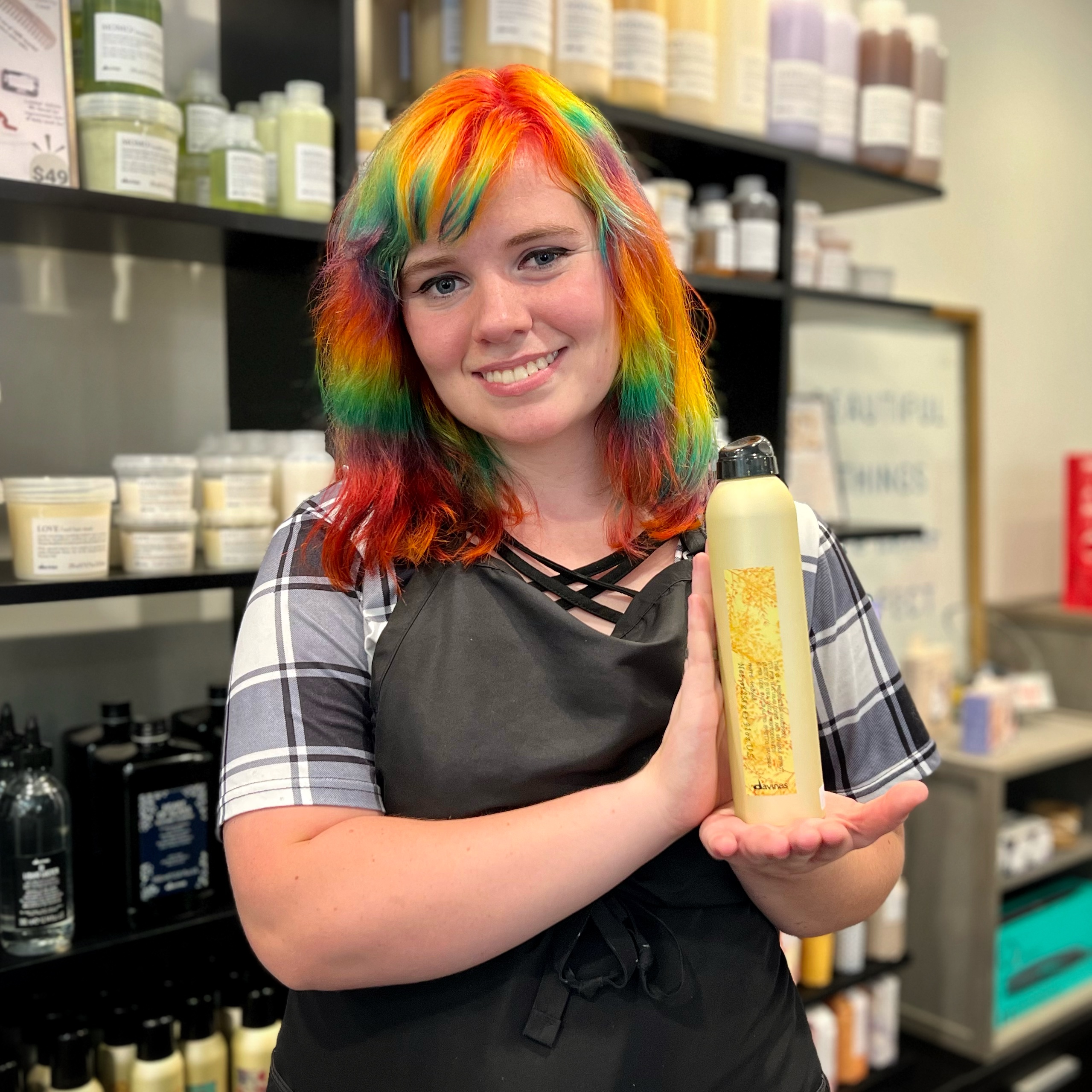 Our hair stylist Sam holds Davines This Is A Perfecting Hairspray.