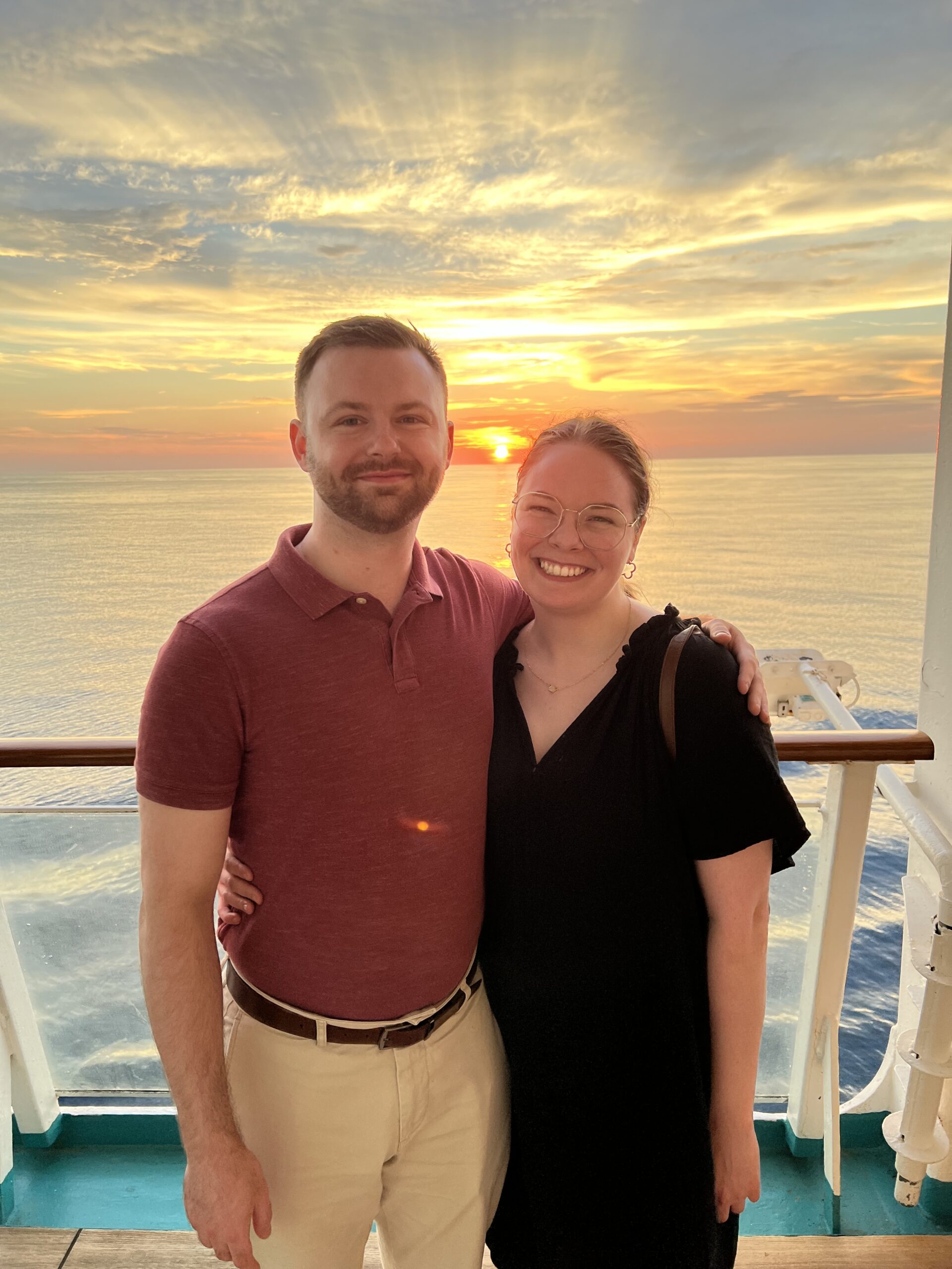 Nicole and her boyfriend, Ben, pose for a photo on their cruise ship's deck overlooking an orange sunset.