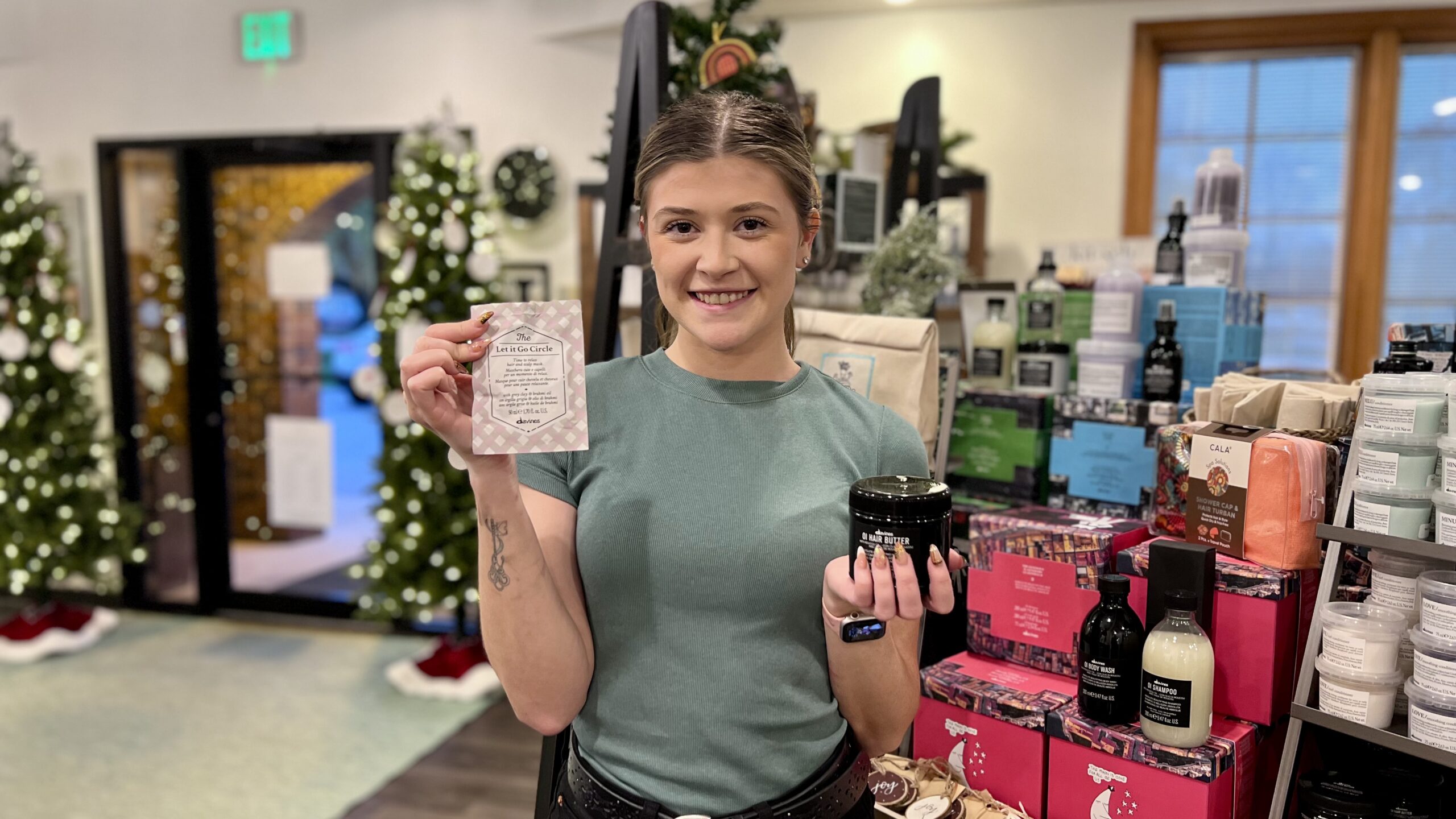 Our hair stylist Jaidyn holds Davines' Let It Go hair mask and OI Hair Butter, two products she recommends to care for your hair this holiday season.