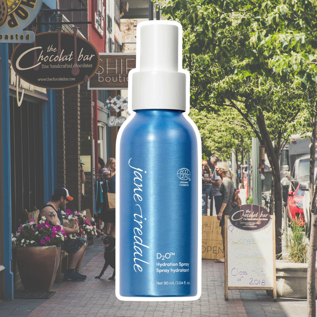Jane Iredale's D2O Hydration Spray against a background of a small town's main street shops.