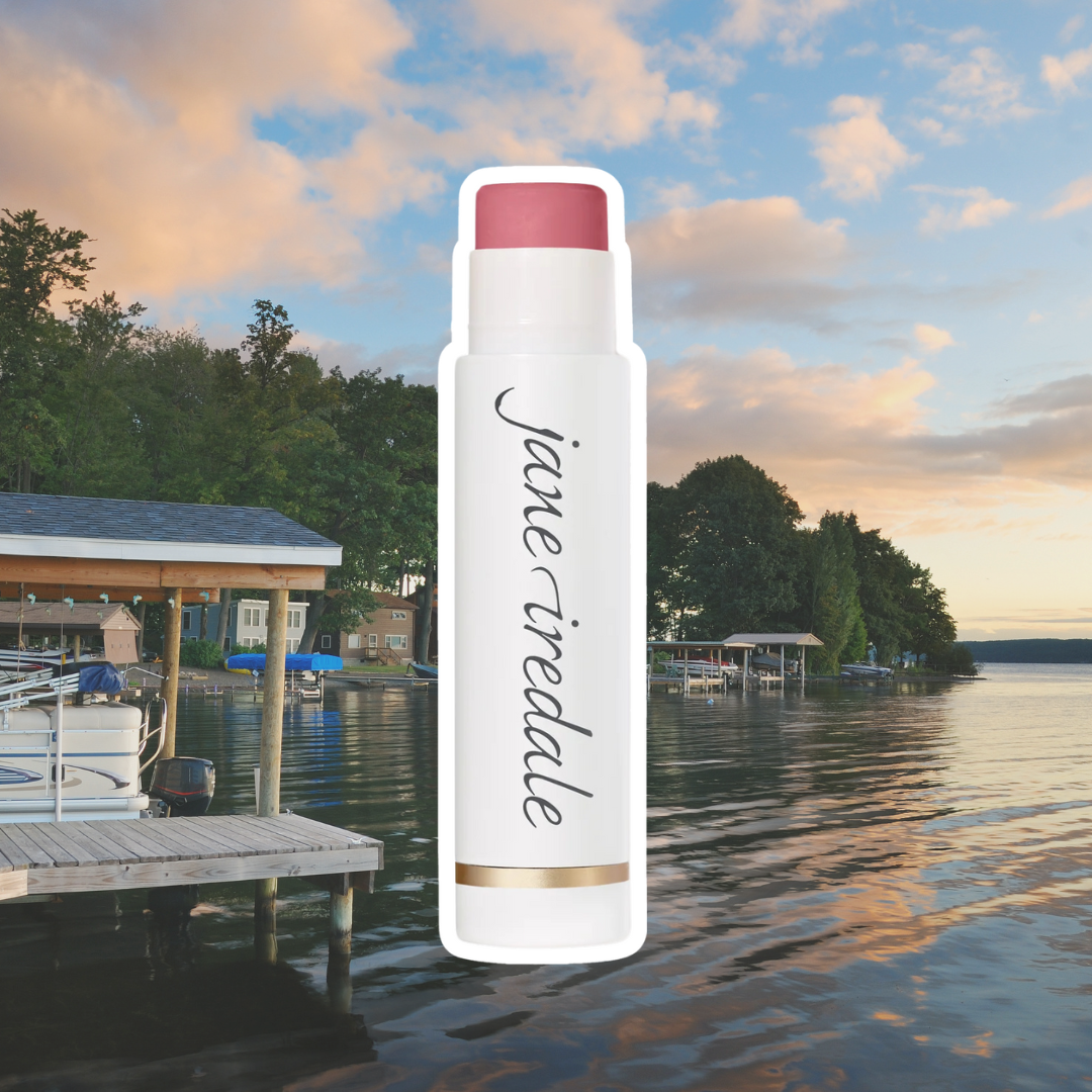 Jane Iredale's LipDrink Lip Balm against a background of a sunset over a lake and dock.