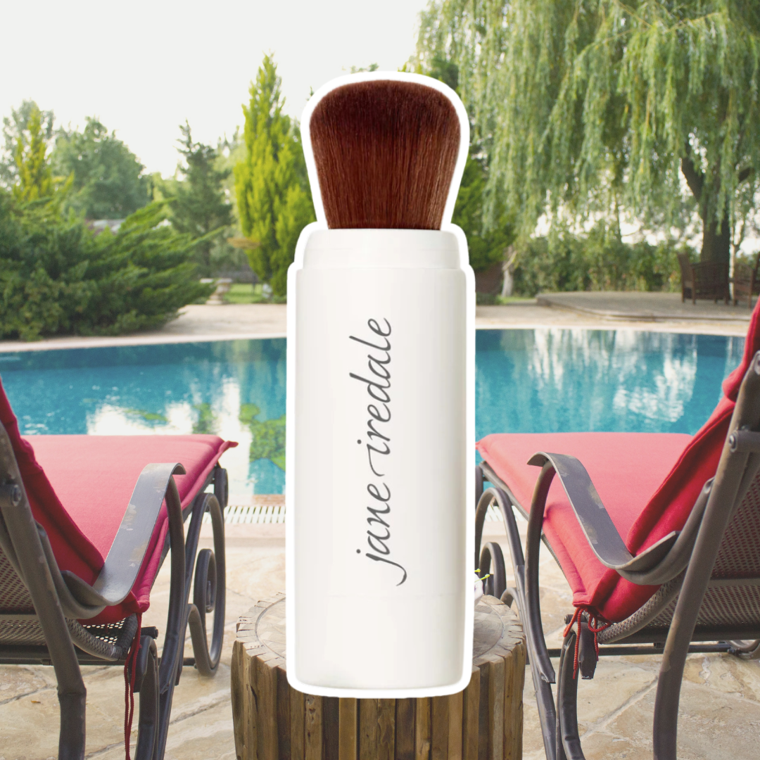 Jane Iredale's Powder-Me Dry Sunscreen against a background of two red lounge chairs by the pool.