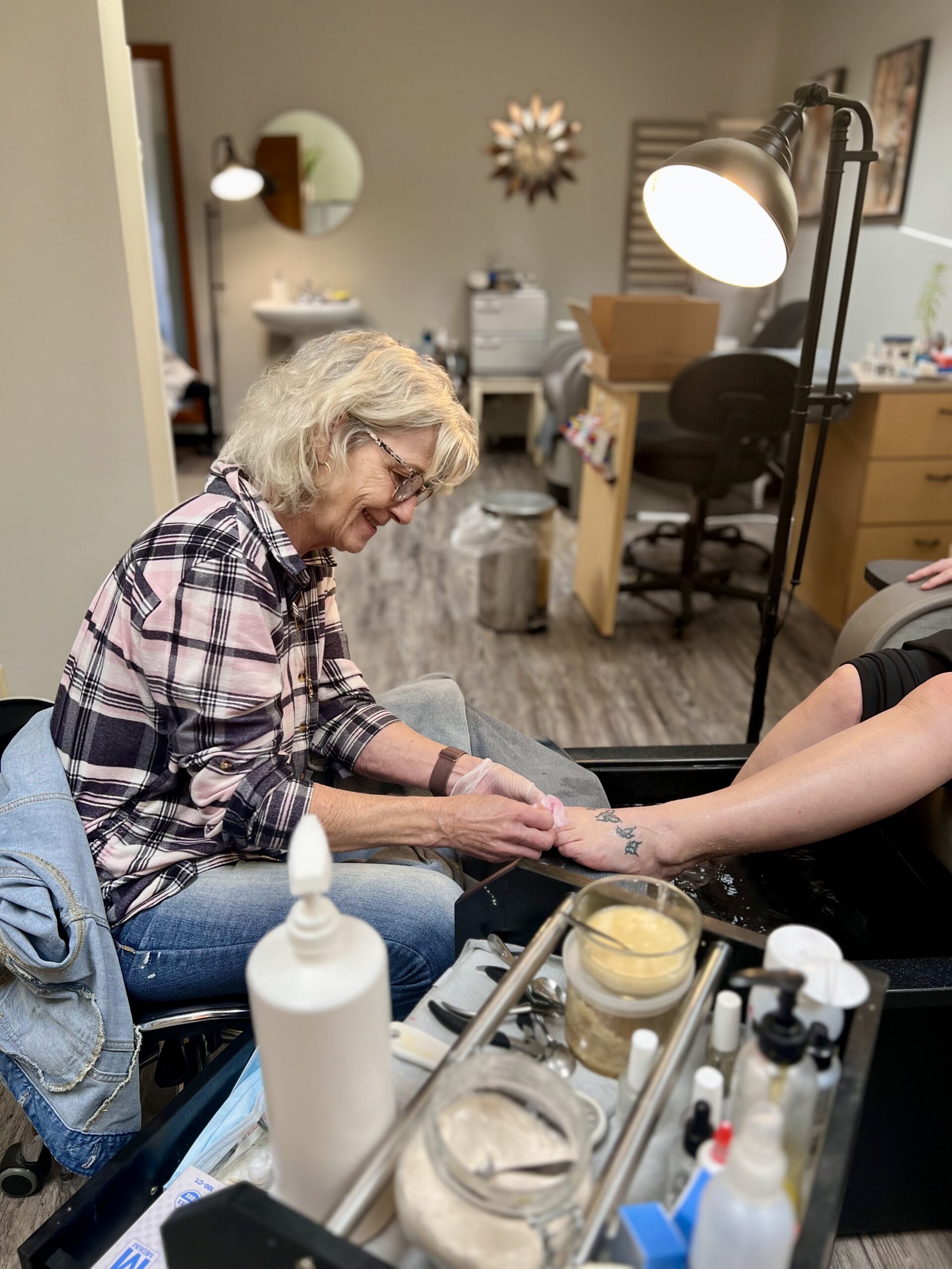 Our nail technician Teena removes her guest's nail polish before beginning their Honey Citrus Ale Pedicure.