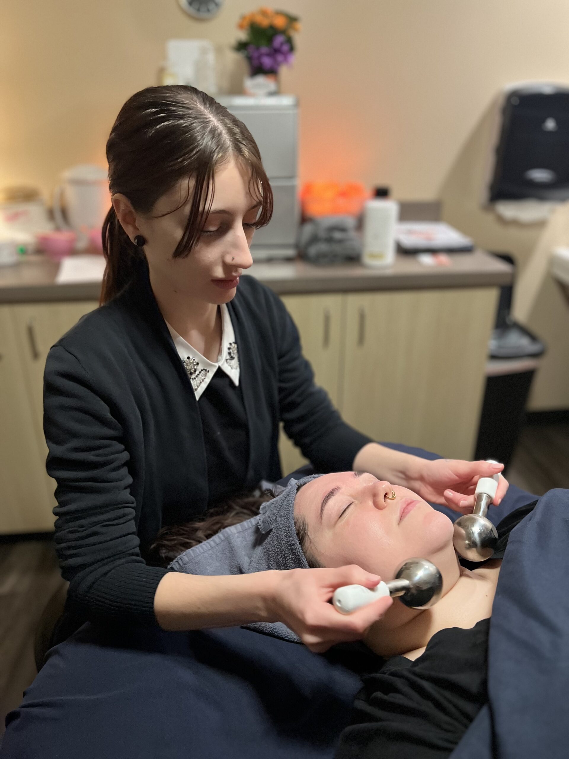 Our esthetician Nicole massages our esthetician Morgan's with chilled massage globes during her Lemon Meltaway Illuminating Facial.
