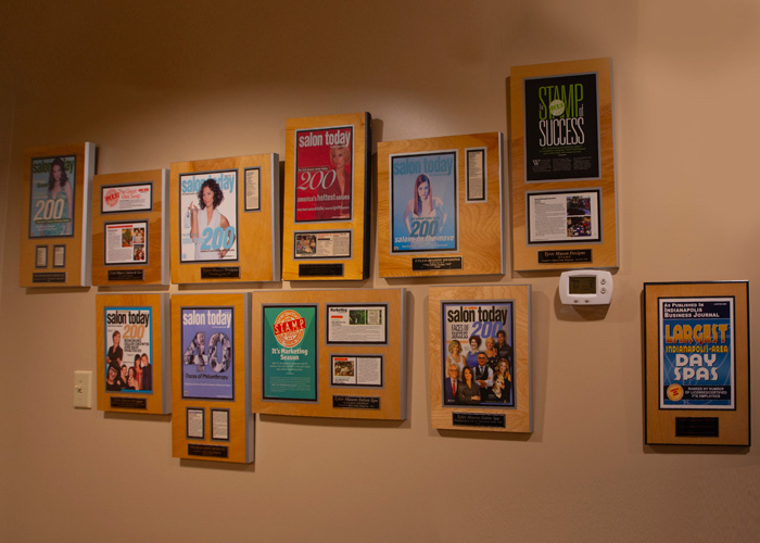 A wall displays multiple award plaques and framed magazine covers recognizing achievements, including several from Salon Today and a few other publications. - Tyler Mason Salon + Spa in Indianapolis, IN