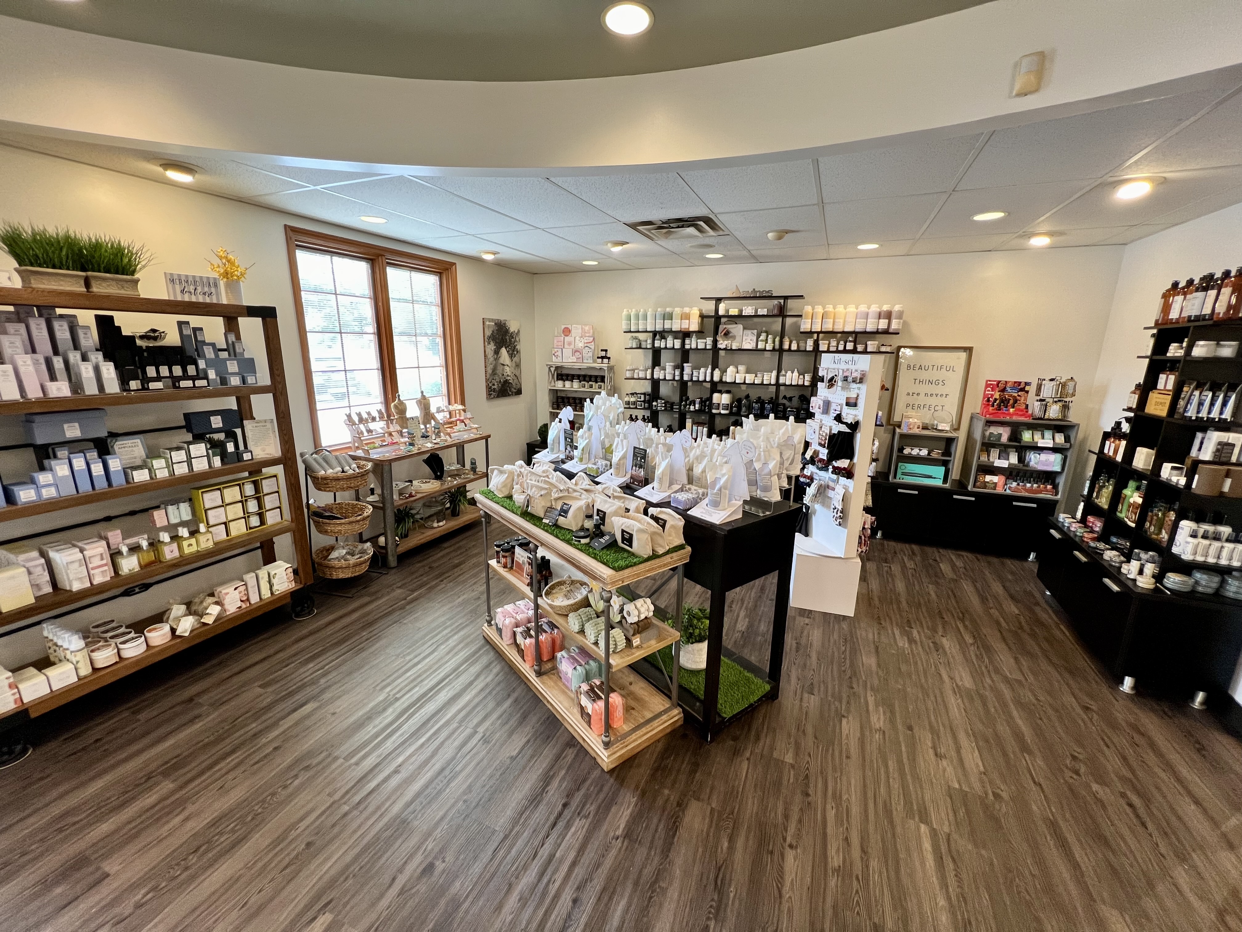 A well-lit store interior with shelves and tables displaying various skincare, beauty, and wellness products on a wood floor. - Tyler Mason Salon + Spa in Indianapolis, IN