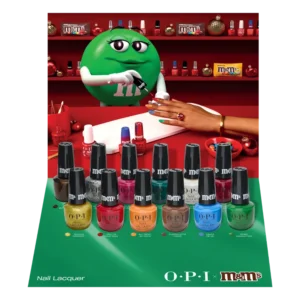 The Green M&M character paints a fingernail in front of the twelve colorful nail polish bottles from OPI’s Most Requested Fall 2026 Collection (Copy). - Tyler Mason Salon + Spa in Indianapolis, IN